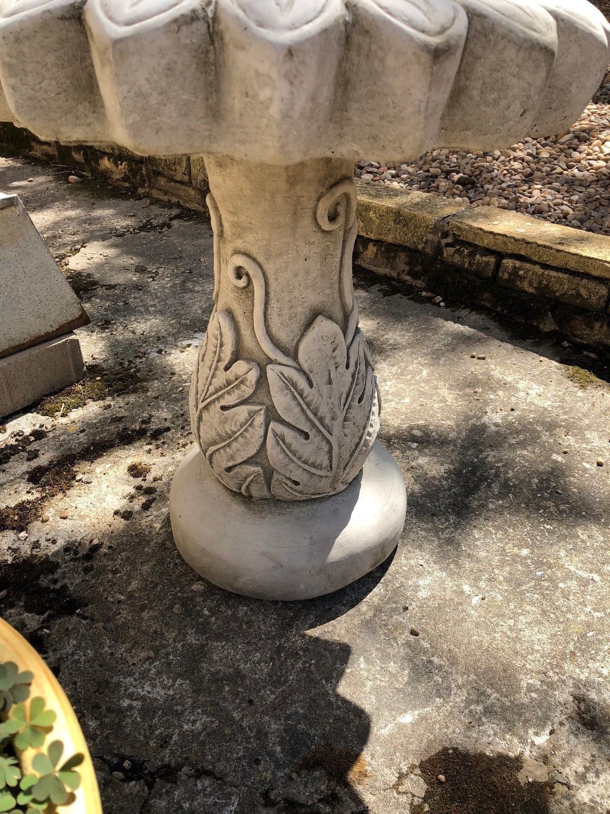 Detailed view of the carved leaf base on the stone sunflower bird bath. Elegant and sturdy garden sculpture made from limestone.