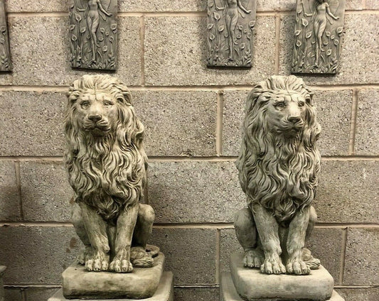 Set of stone lion statues with plinths for garden decor, featuring detailed manes and a durable limestone finish. Ideal for outdoor entrances or patios.