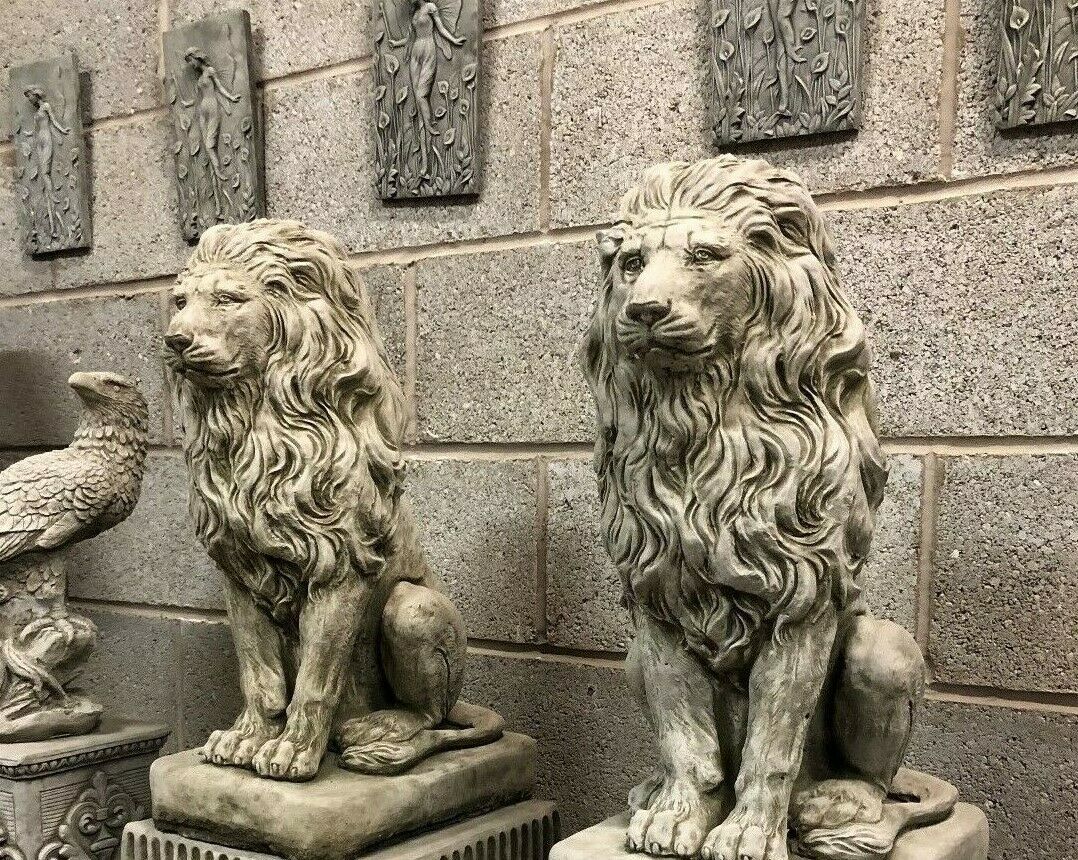 Pair of stone lion statues on decorative plinths, perfect for enhancing garden entrances with a regal and timeless look.