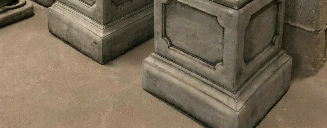 Base view of two square stone plinths designed to support lion statues, featuring classic panel accents for garden use.