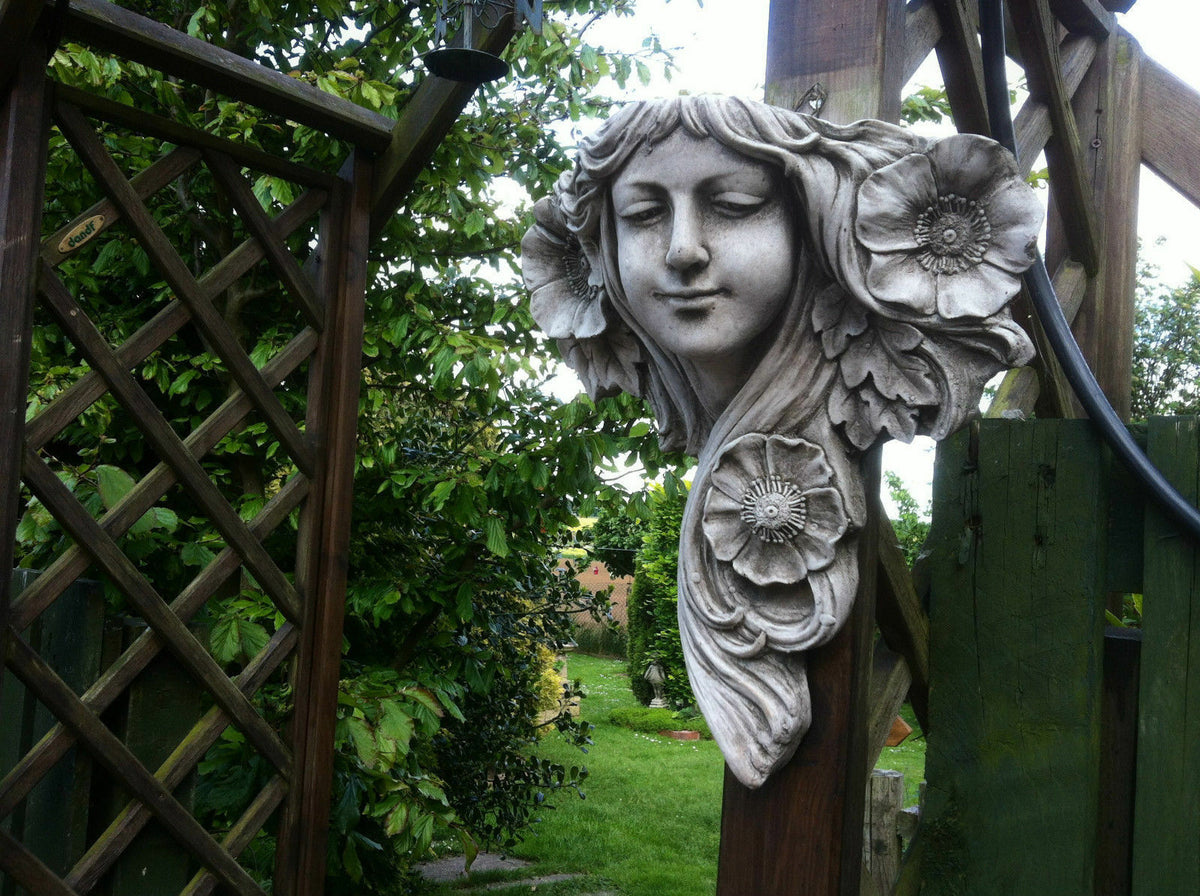 Art Nouveau Garden Plaque - Lady Wall Decor in limestone mounted on wooden trellis, surrounded by lush greenery in a garden setting.