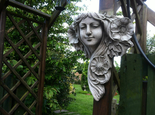 Art Nouveau Garden Plaque - Lady Wall Decor in limestone mounted on wooden trellis, surrounded by lush greenery in a garden setting.