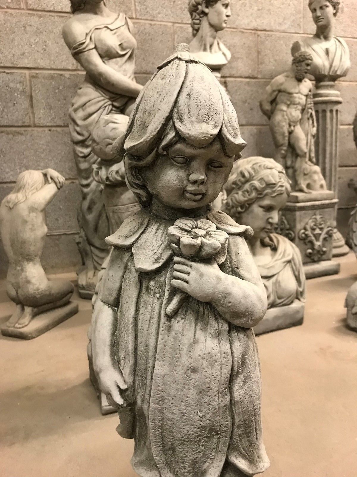 Close-up of Bluebell Girl Statue holding a flower, showcasing fine limestone craftsmanship. A decorative garden ornament for UK homes.