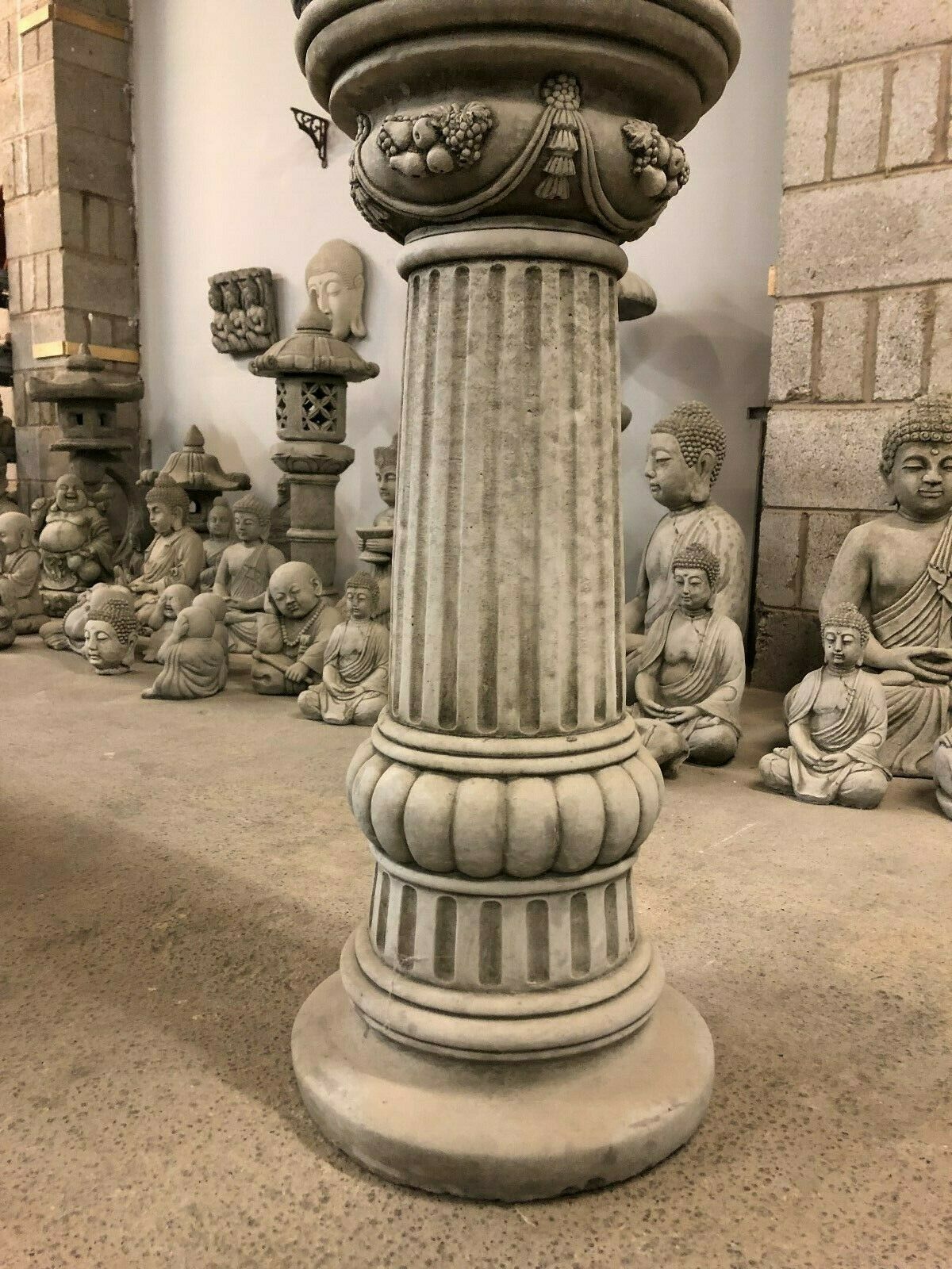 Detailed view of the ornate pedestal base of Buddha Head Garden Statue. Limestone column adds elegance to outdoor spaces.