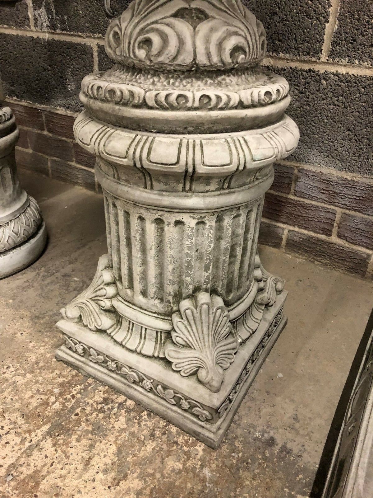 Detailed base of a stone Bacchus urn planter plinth with fluted column and shell motifs, perfect for outdoor display.