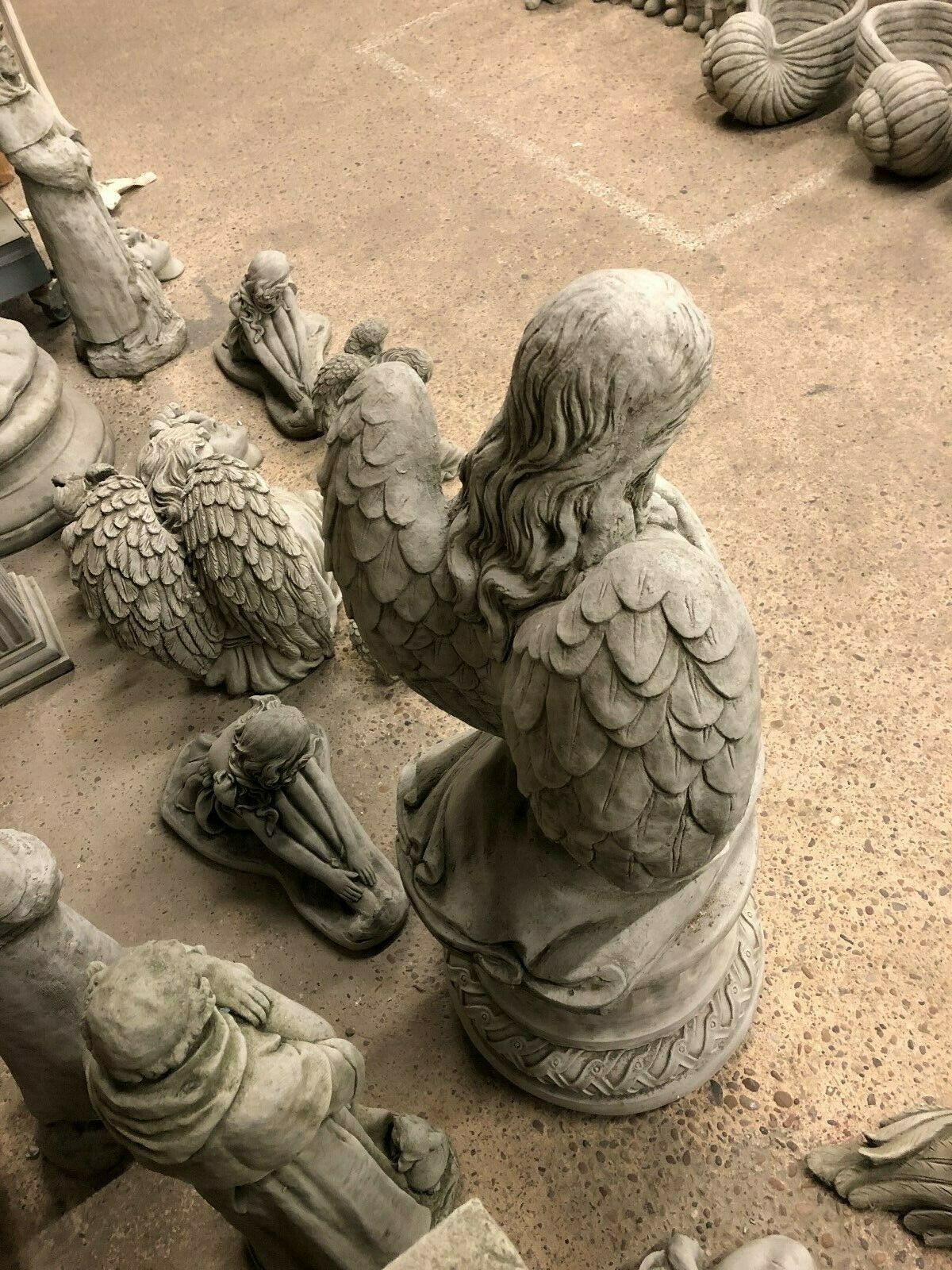 Top-down view of kneeling angel garden statue showing detailed wing carvings and solid stone craftsmanship for outdoor decor.