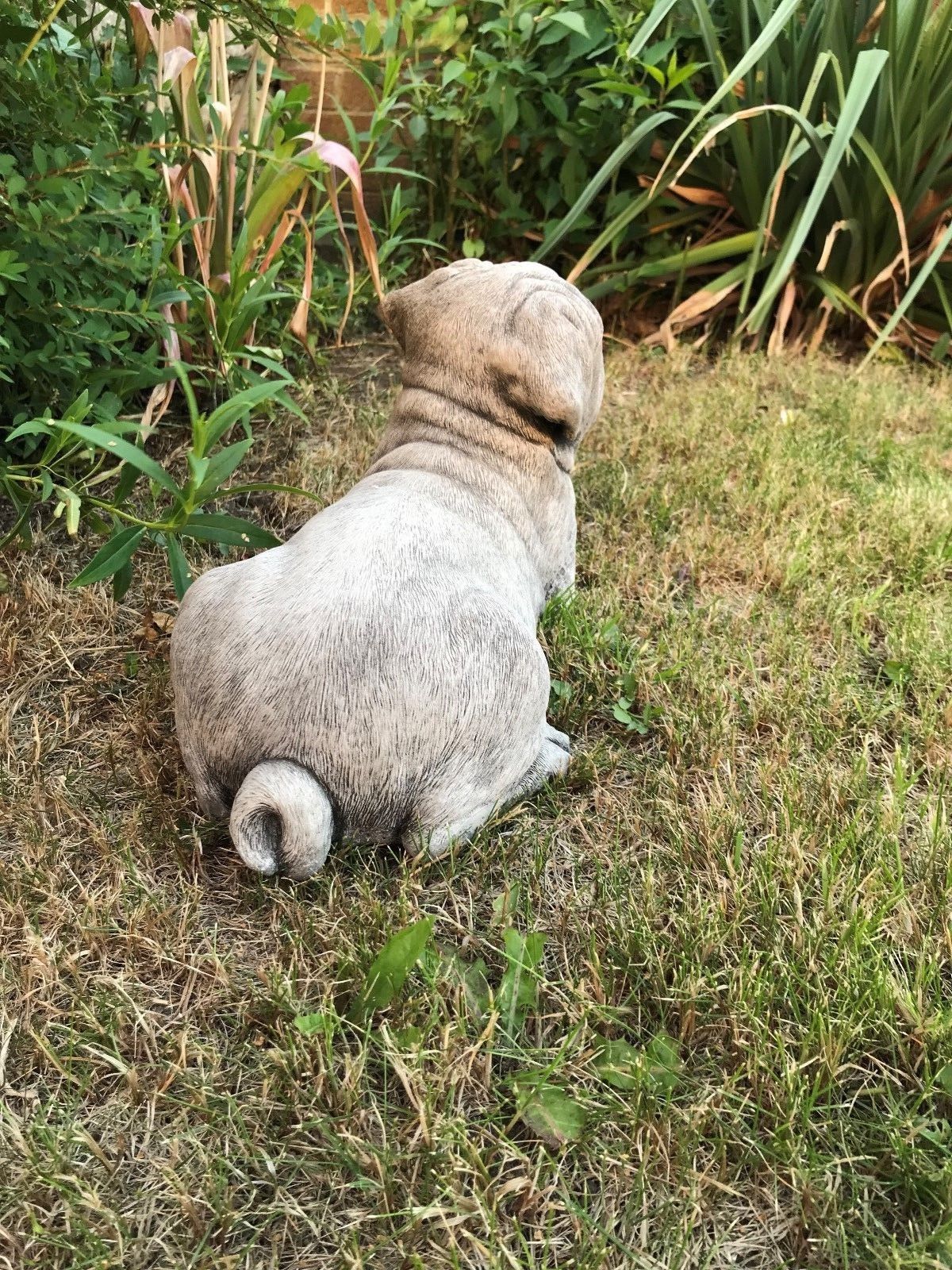 Rear view of Stone Pug Sculpture - Garden Ornament showing curled tail and textured stone finish, perfect for garden landscapes.