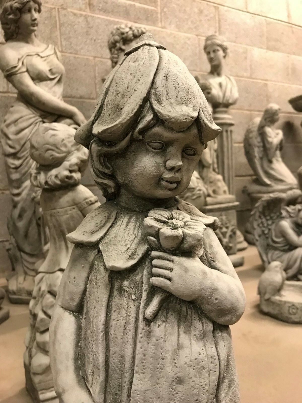 Detailed view of the Bluebell Girl Garden Statue's face and flower, highlighting its artistic design and weather-resistant stone finish.