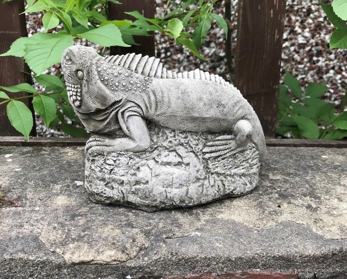 Single iguana garden statue from the Stone Collection on a stone ledge, featuring textured limestone and lifelike reptilian detail.