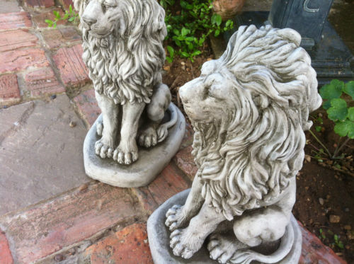 Pair of stone lion garden statues with antique grey finish on brick patio, ideal for outdoor decor and entryway guardians.