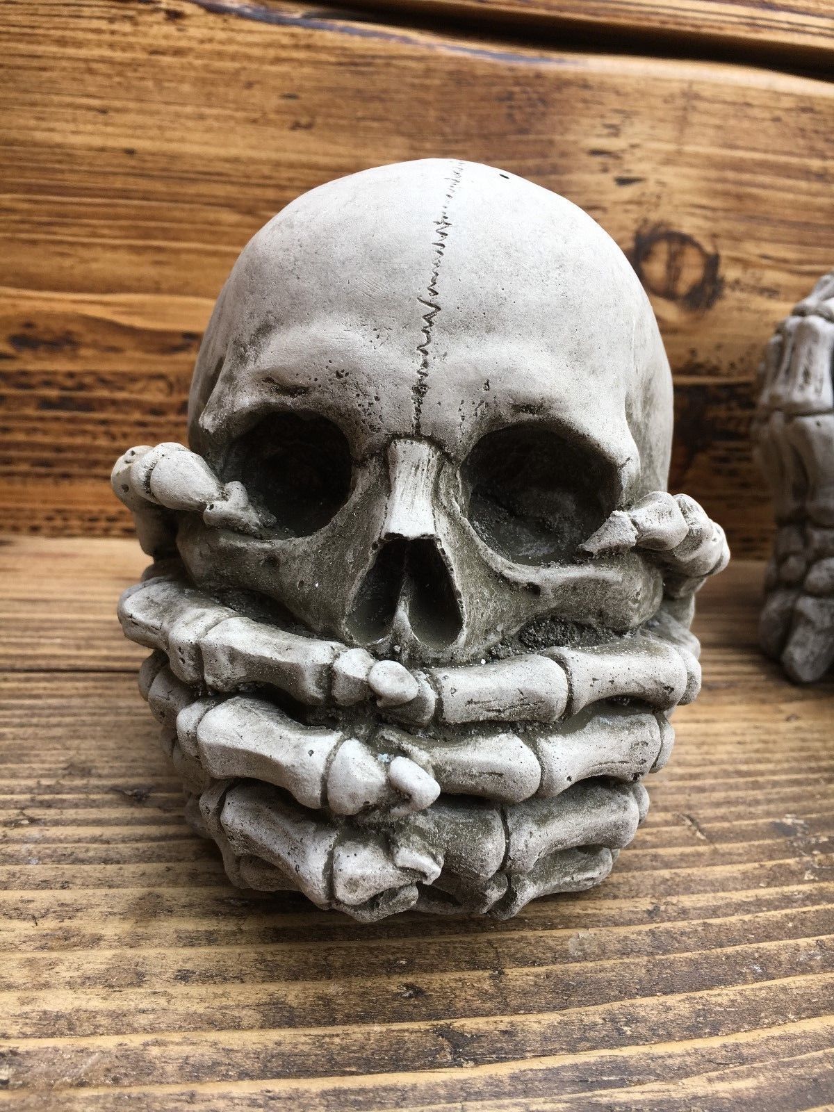 Detailed 'Speak No Evil' skull garden sculpture with skeletal hands over the mouth, crafted from durable limestone for gothic outdoor decor.