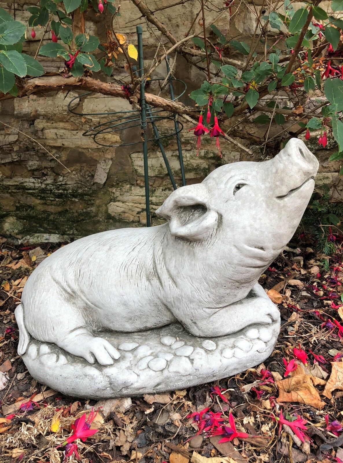 Front-facing Stone Pig Sculpture Garden Ornament with joyful expression and pebble-textured base. Handmade in the UK for outdoor garden decoration.
