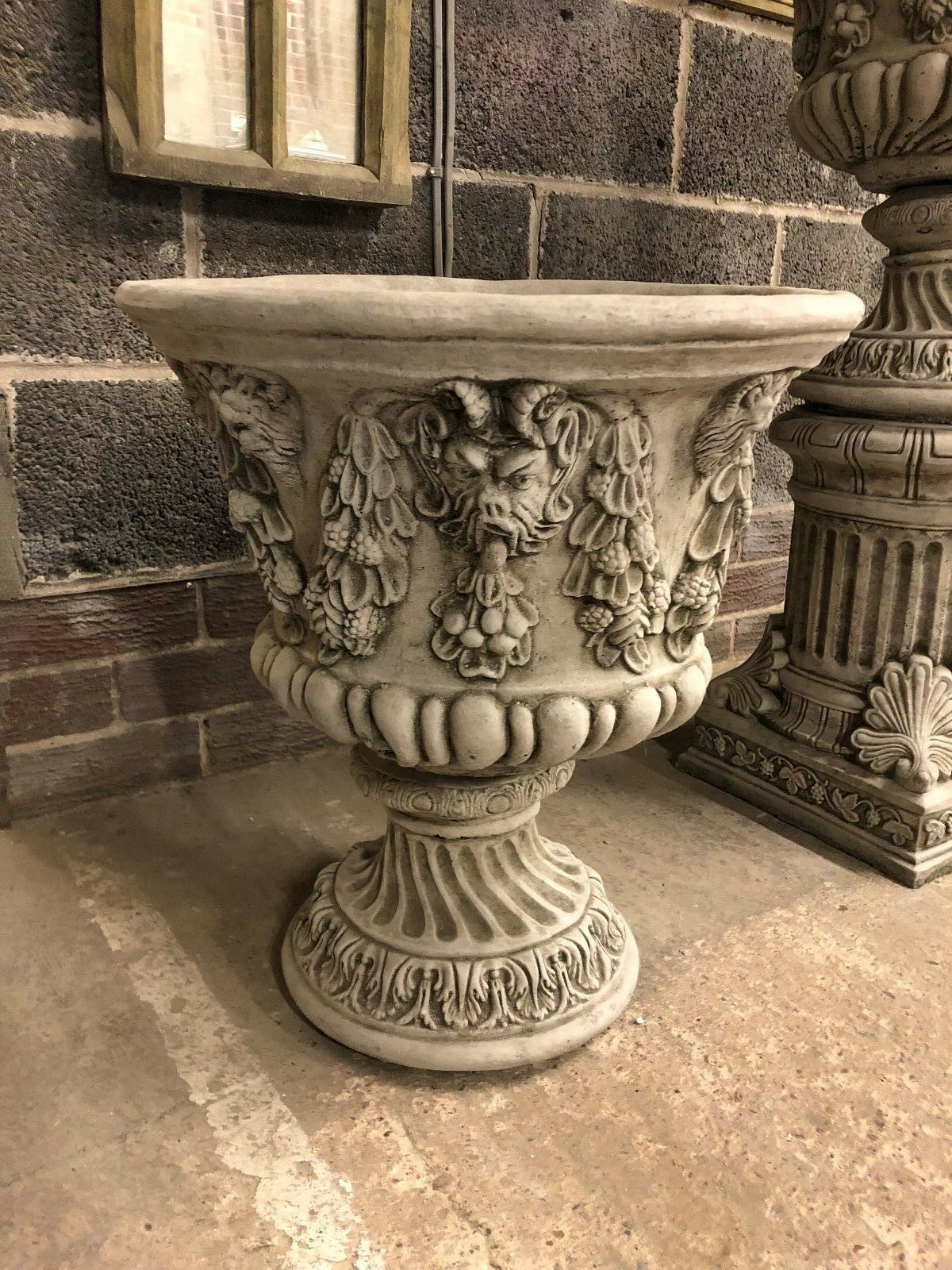 Stone Bacchus urn planter with lion face and garland detailing, ideal for enhancing garden aesthetics with classical design.