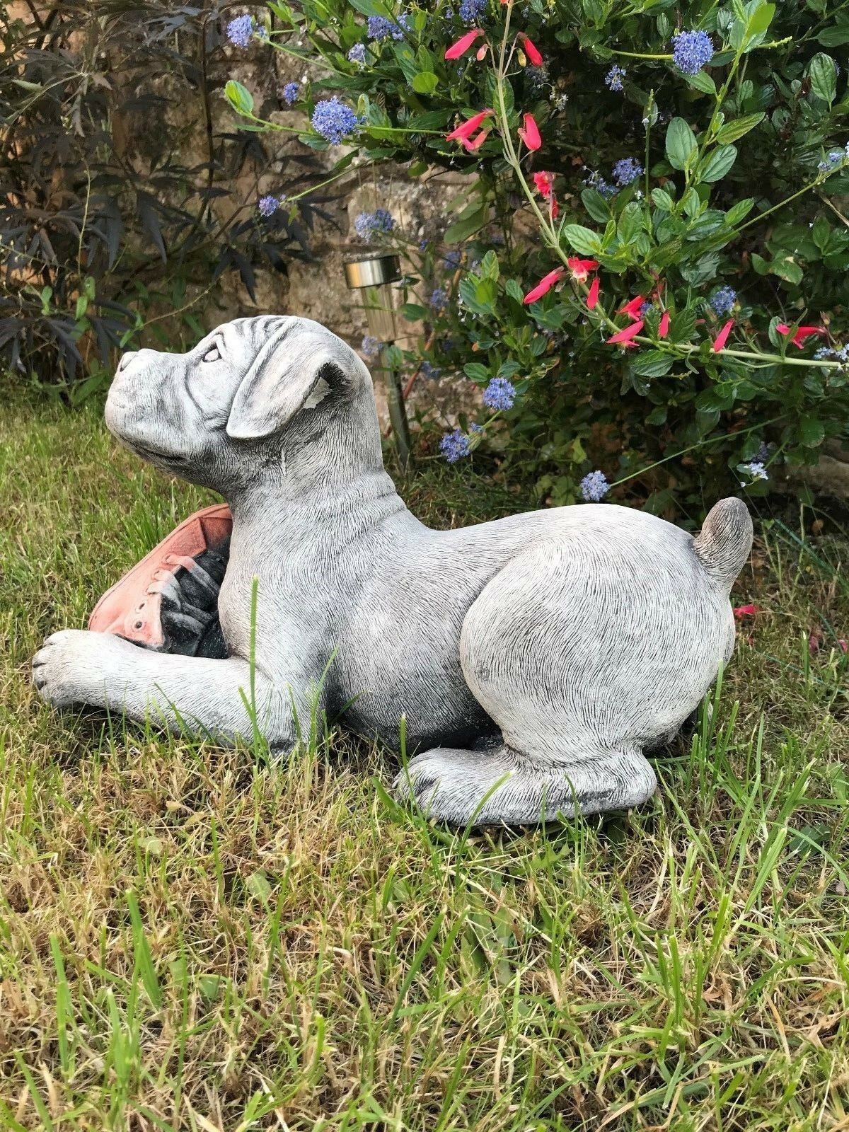 Stone Boxer Puppy Garden Sculpture with realistic fur detailing, lying on grass with a red shoe, designed for outdoor decorative use.