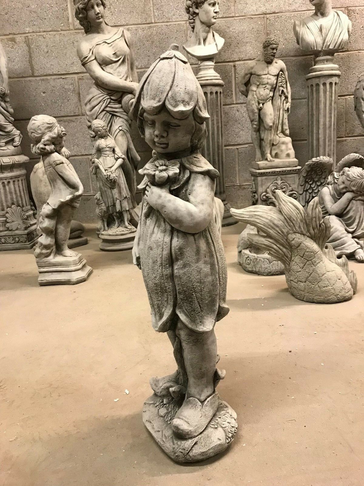Side profile of the Bluebell Girl Garden Statue showing textured limestone and floral hat, ideal for outdoor garden decor.