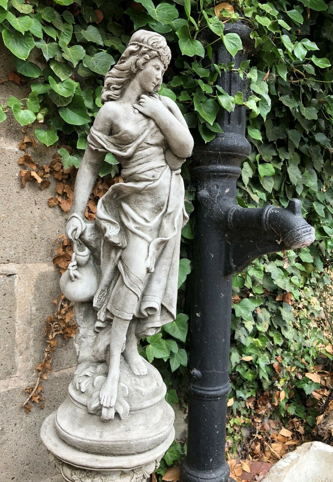 Close-up of Garden Stone Statue - Jug Lady Plinth showing intricate drapery and jug detail, crafted in durable antique grey limestone.