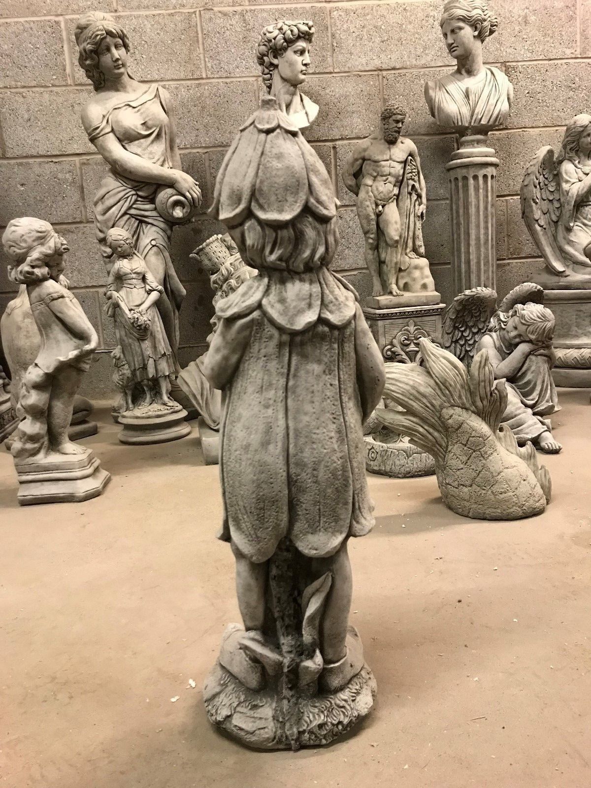 Rear view of the Stone Bluebell Girl Statue with petal-like cloak, crafted for 360-degree visual appeal in garden settings.