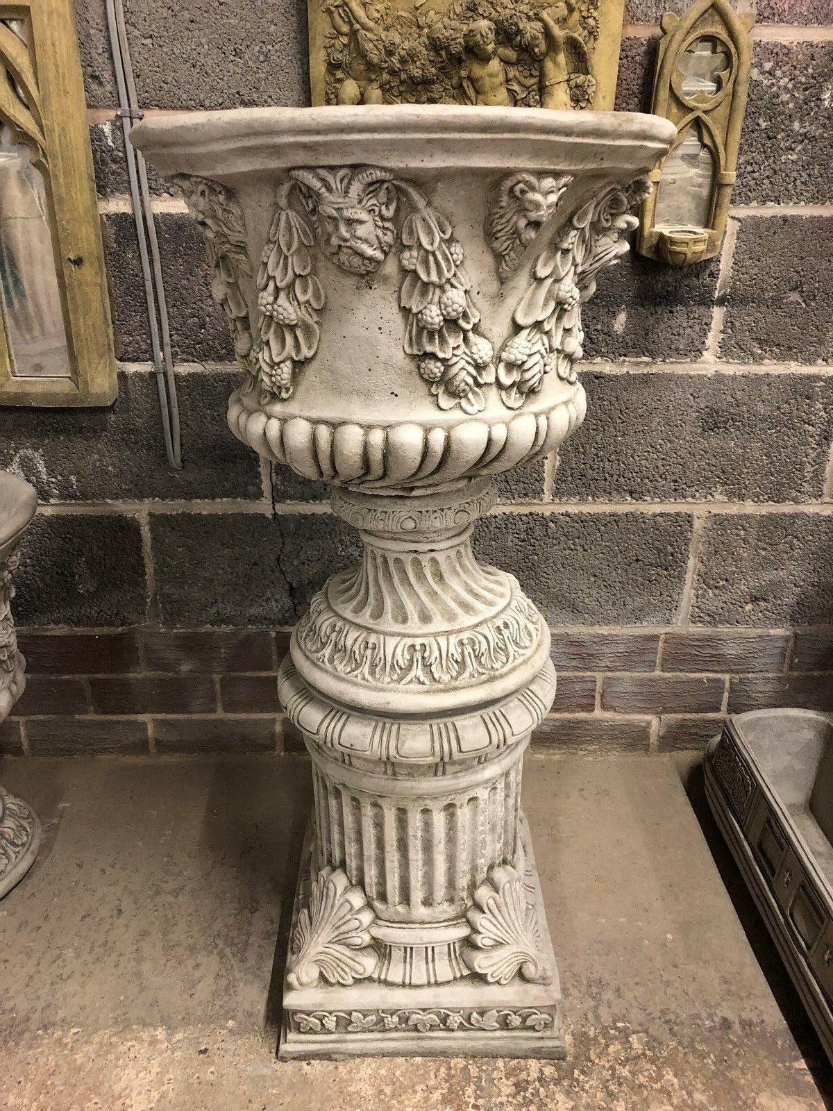 Front view of a Bacchus stone urn planter on a detailed plinth, showcasing classical ornamentation for garden elegance.