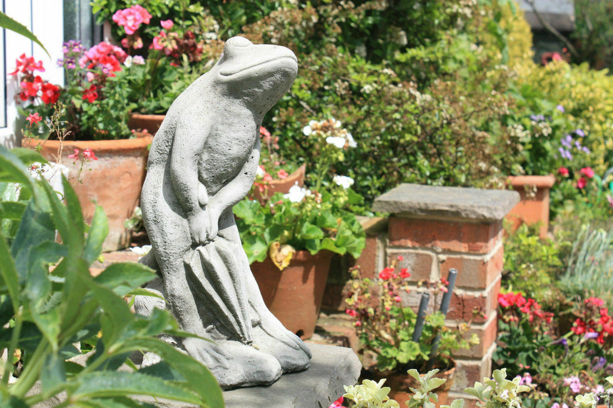Elegant Stone Frog Garden Ornament with Umbrella placed in a vibrant flower garden, perfect for enhancing outdoor spaces with charm.