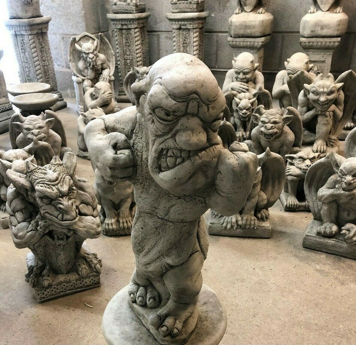 Close-up of aggressive stone boxer garden statue surrounded by gargoyle sculptures, from Bare Knuckle Boxer Statues collection.