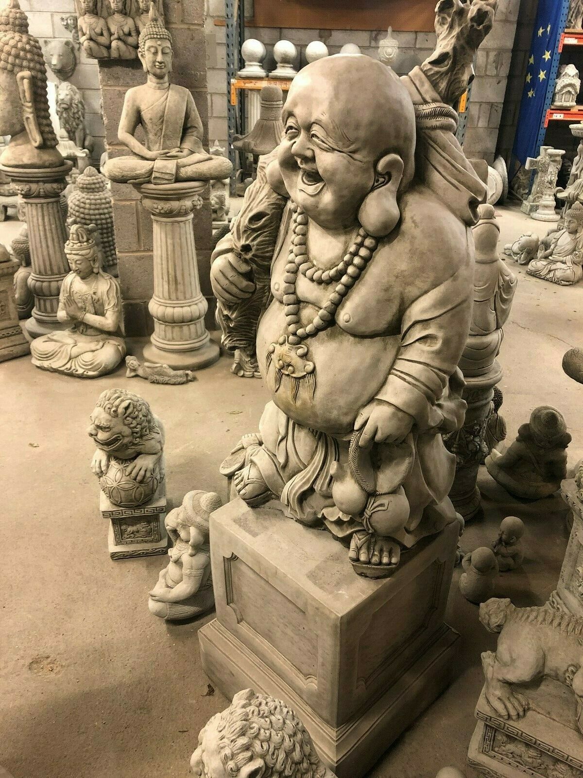 Laughing Buddha Statue on pedestal in stone, perfect for indoor zen decor or garden fortune ornament. Features intricate detailing and solid design.