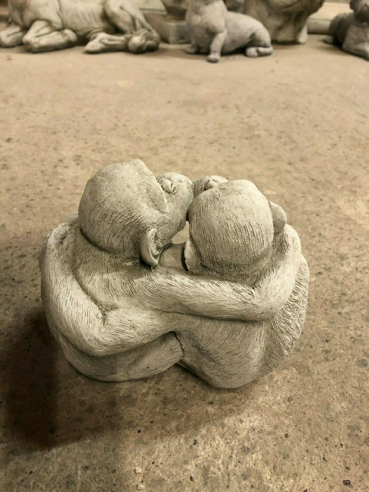 Back view of hugging limestone monkey couple sculpture, a heartwarming garden ornament for outdoor spaces.