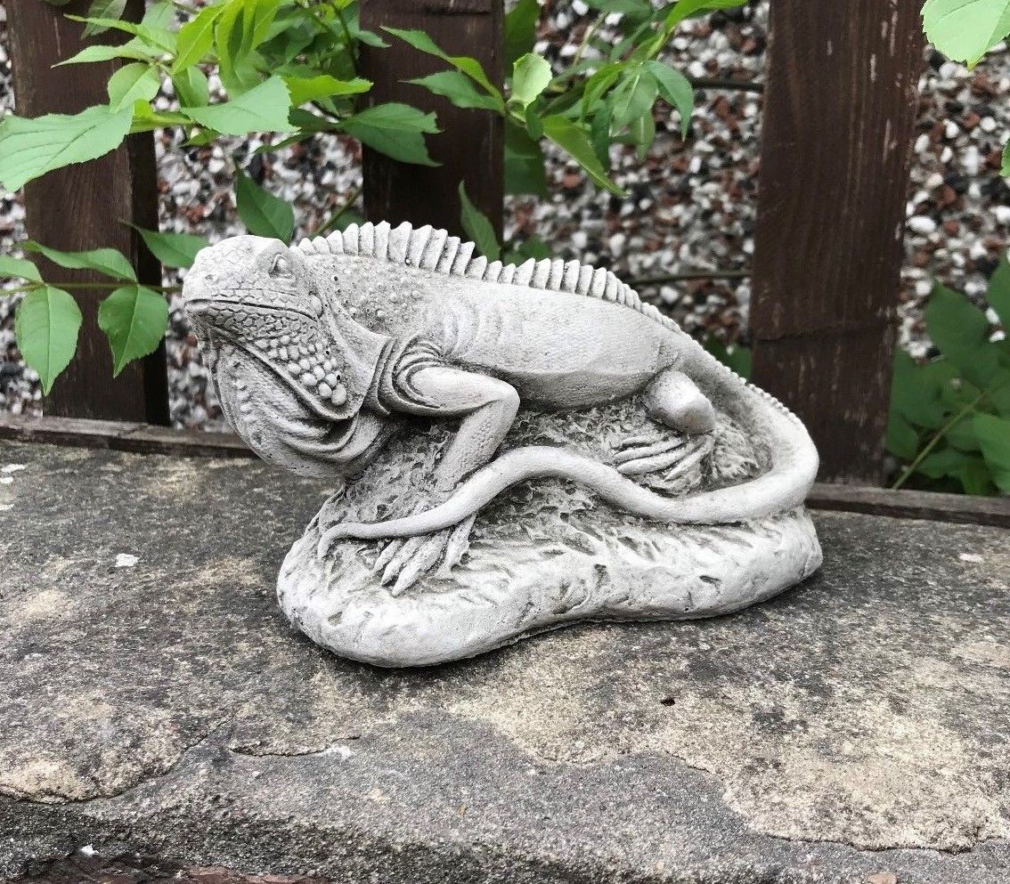 Detailed stone iguana garden ornament from the Iguana Garden Ornaments - Stone Collection, placed on a stone ledge with rustic background.