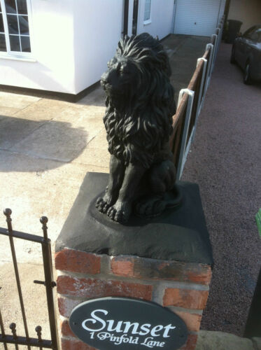 Black stone lion statue mounted on a brick pillar at a gate entrance, adding bold and stylish outdoor decor.