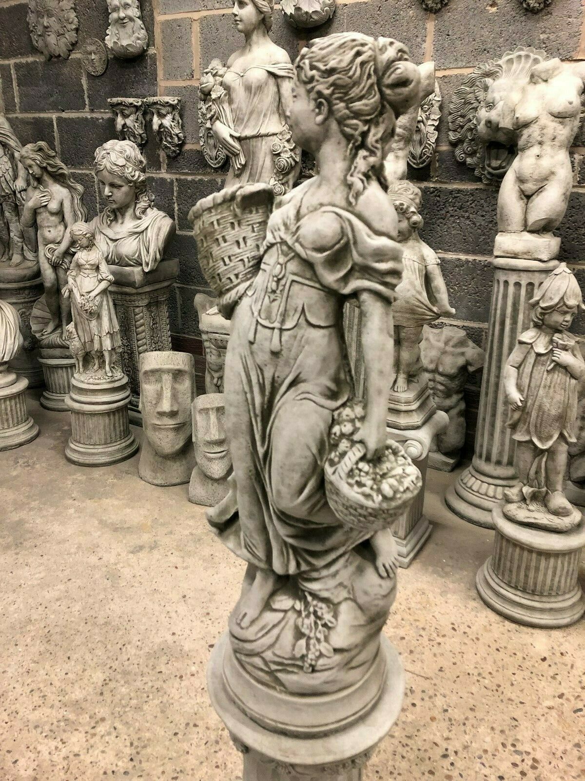 Side profile of Stone Roman Lady Garden Statue with fruit basket, crafted from weatherproof limestone for timeless outdoor charm.