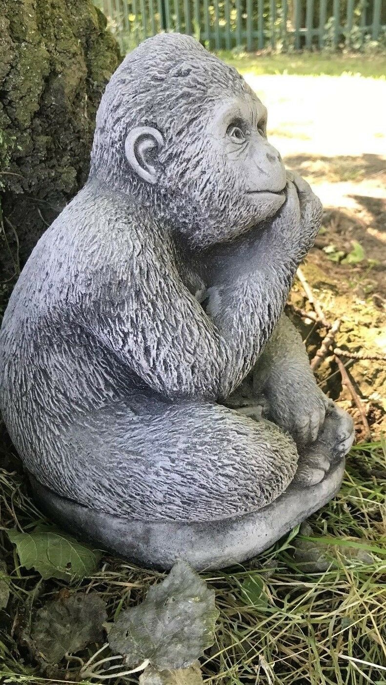 Profile view of antique grey stone gorilla statue sitting cross-legged, perfect for patios, porches, or garden beds.