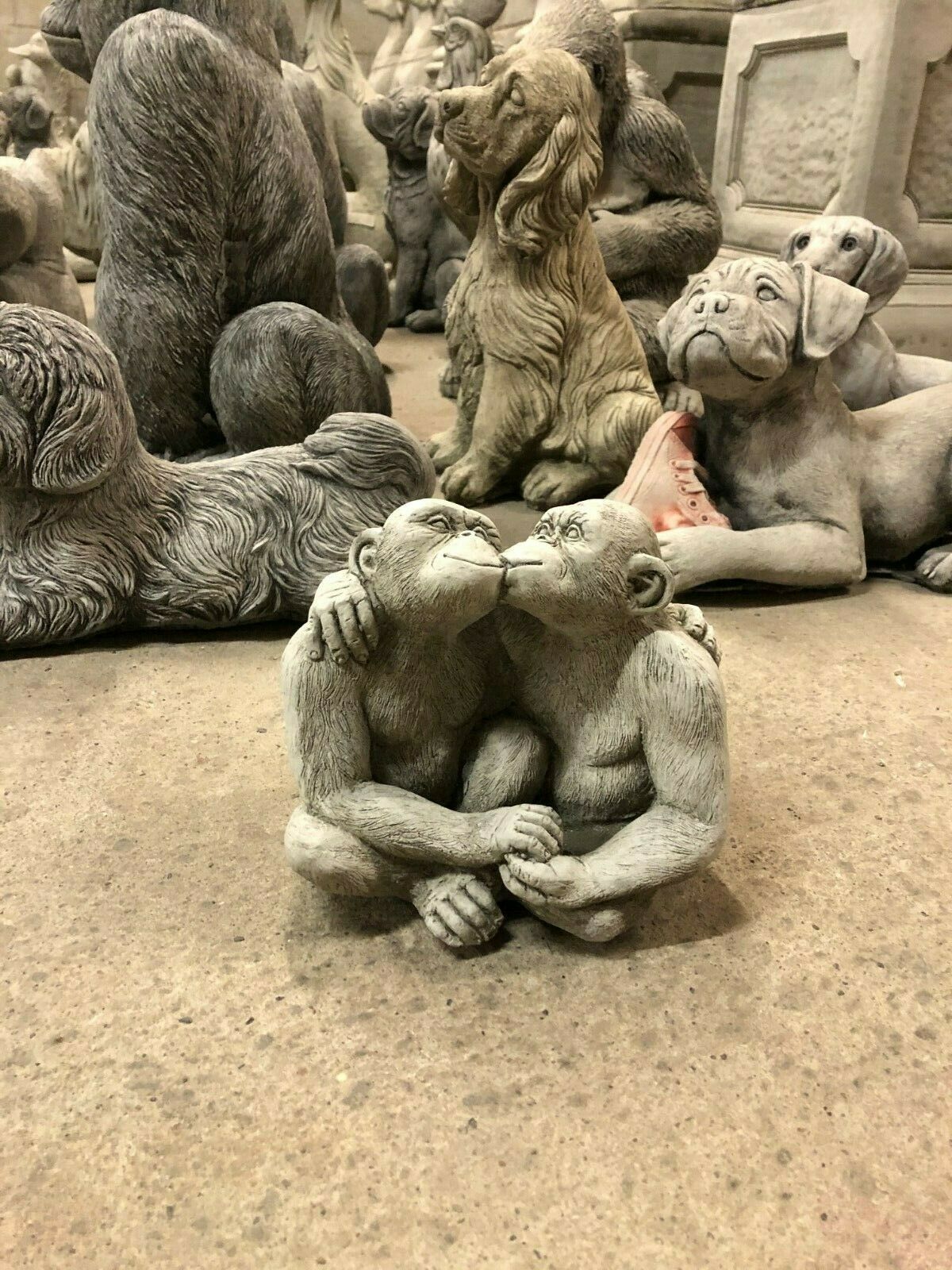 Kissing Monkey Couple Garden Sculpture surrounded by other animal ornaments, ideal for themed garden decoration.