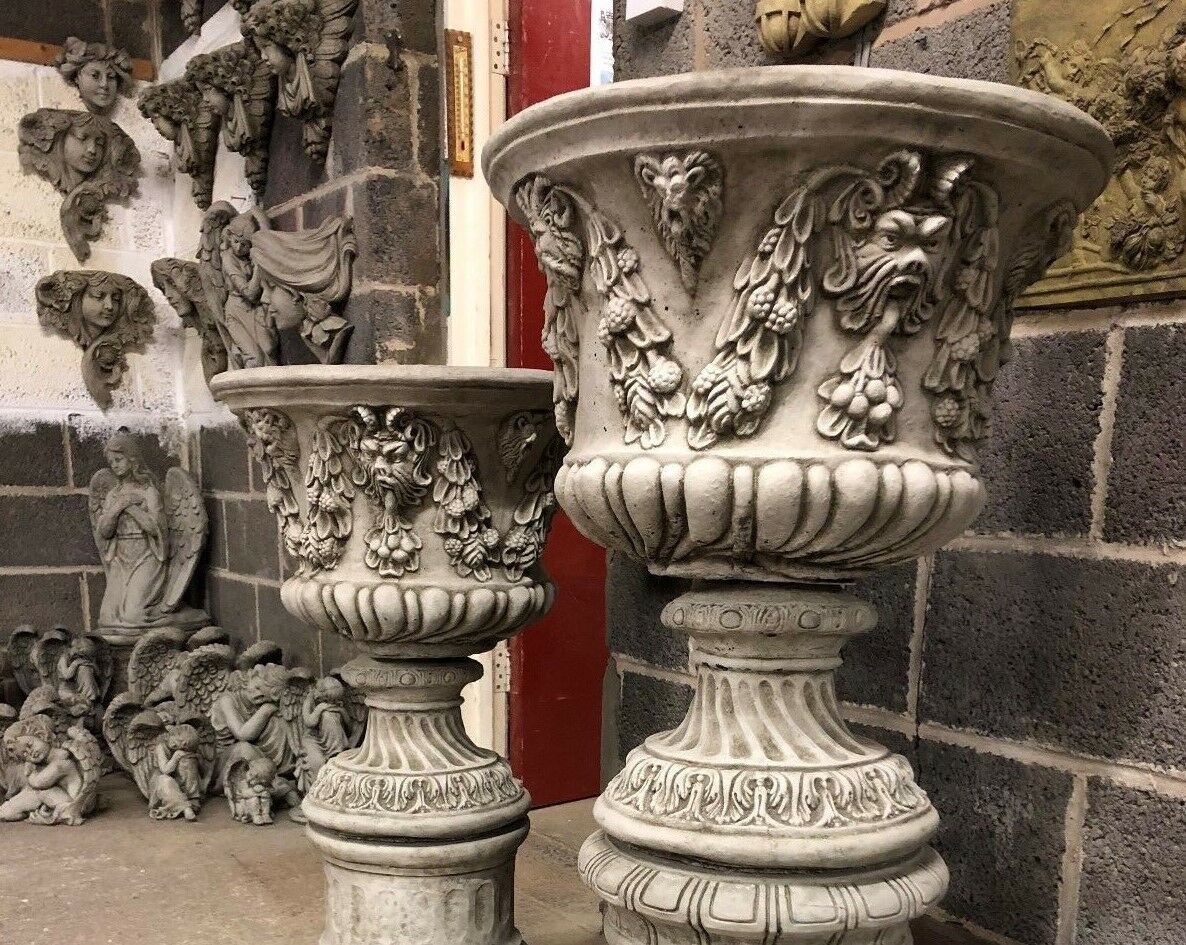Two sizes of Bacchus design stone urn planters side by side, highlighting scale and decorative detail for garden use.