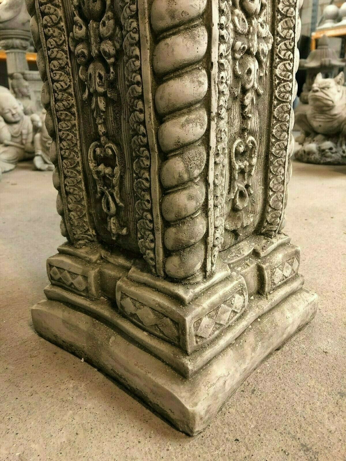 Base detail of tall square garden column in limestone, featuring carved trim and antique finish for elegant outdoor decoration.