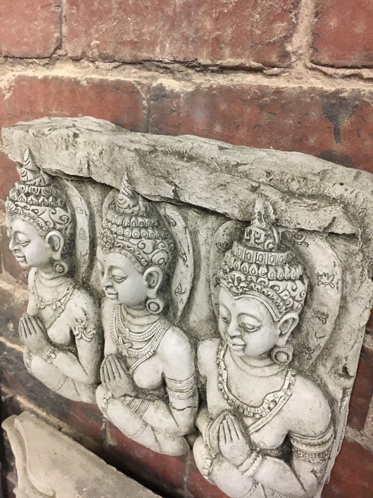 Close-up of Buddha wall plaque from above, highlighting fine stonework. Ideal for home or garden decor with antique limestone texture.