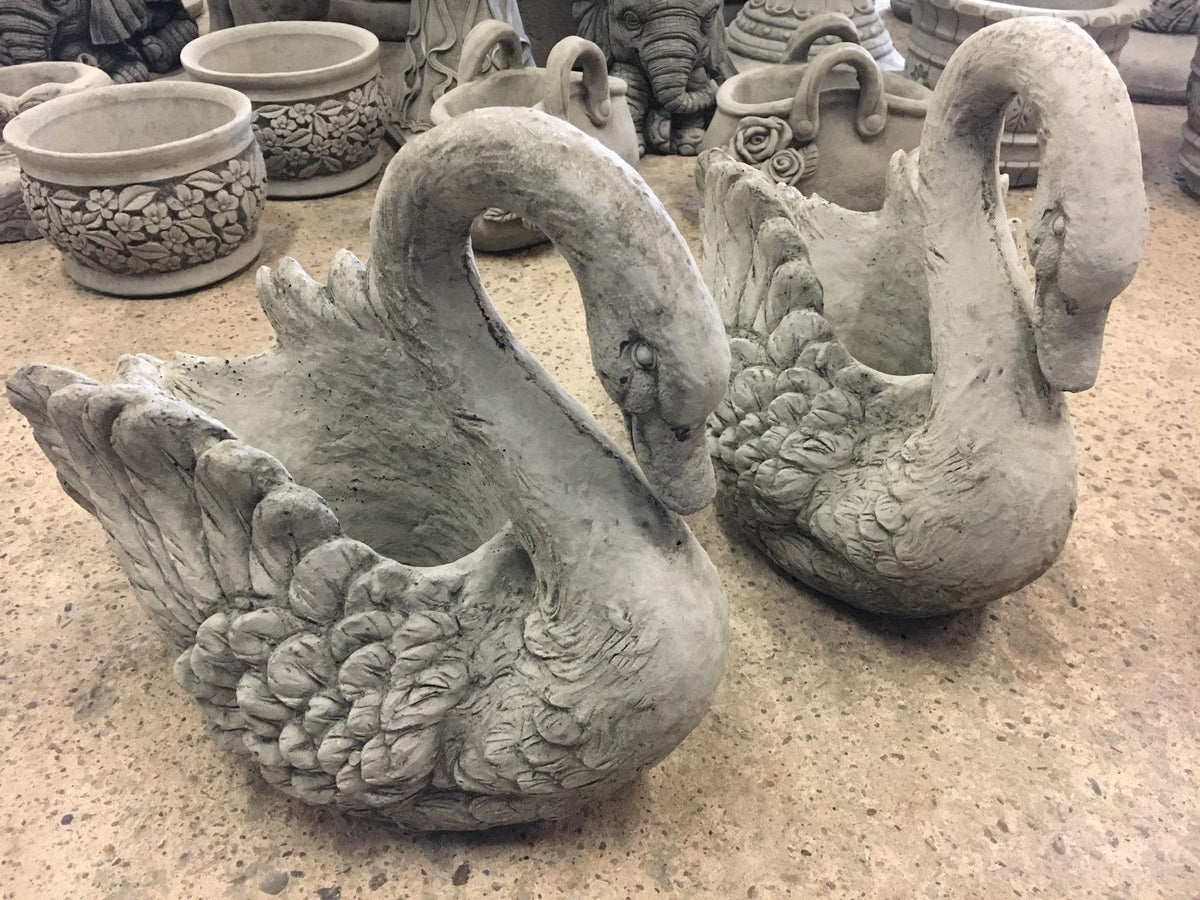 Pair of stone swan planters with drainage hole, crafted from durable limestone for outdoor garden decor. Elegant feather detailing enhances design.