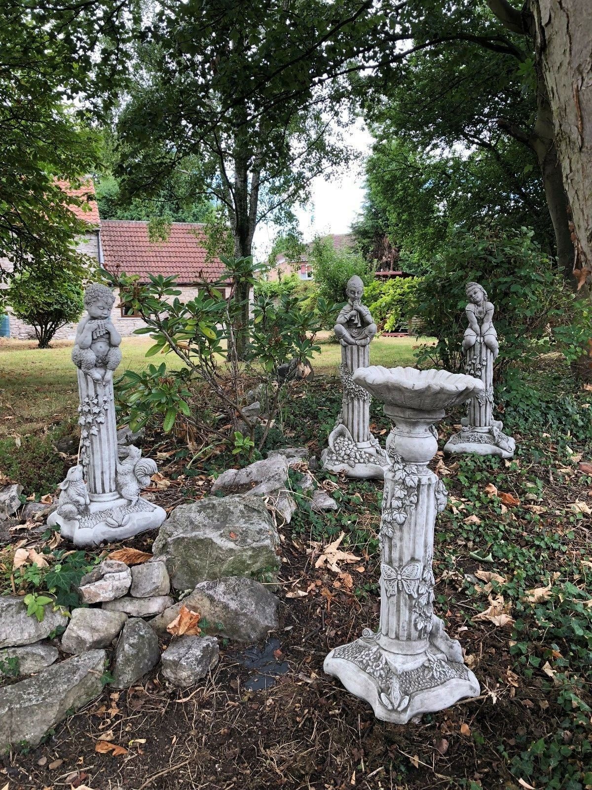 Stunning Stone Garden Statues - Four Seasons Statues displayed in a lush garden setting with detailed seasonal figures on ornate pedestals.