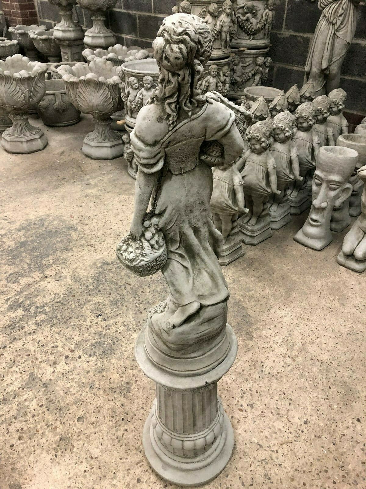 Rear view of Stone Roman Lady Garden Statue on column base, emphasizing flowing dress and basket details in durable limestone.