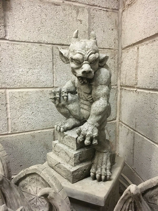 Stone gargoyle statue with menacing expression perched on a pedestal, ideal as a durable garden guardian for gothic outdoor decor.