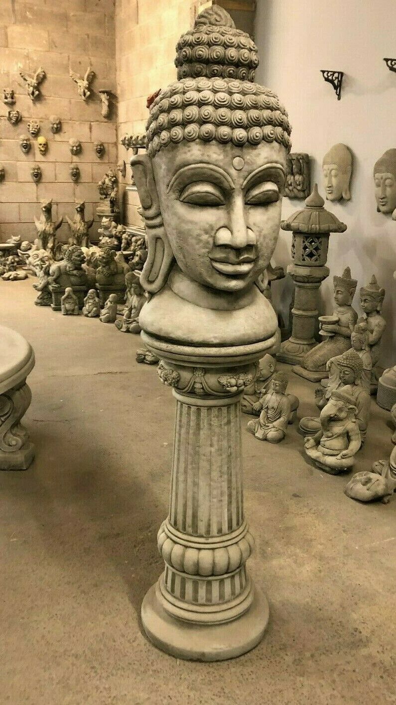 Buddha Head Garden Statue on ornate stone plinth, ideal for outdoor zen garden decor. Handcrafted limestone sculpture for lawn or patio display.