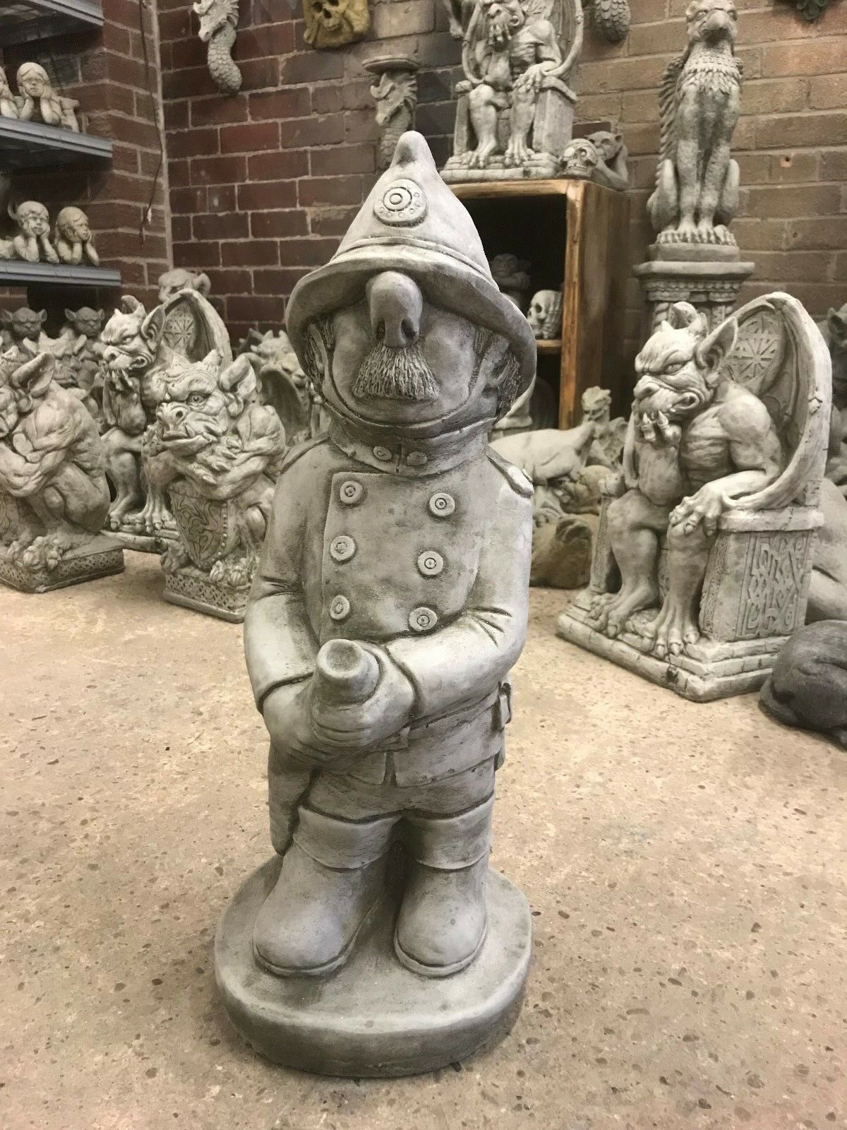 Garden Fireman Statue in antique grey limestone, featuring a detailed firefighter figure with hose, ideal for outdoor decor and weatherproof display.