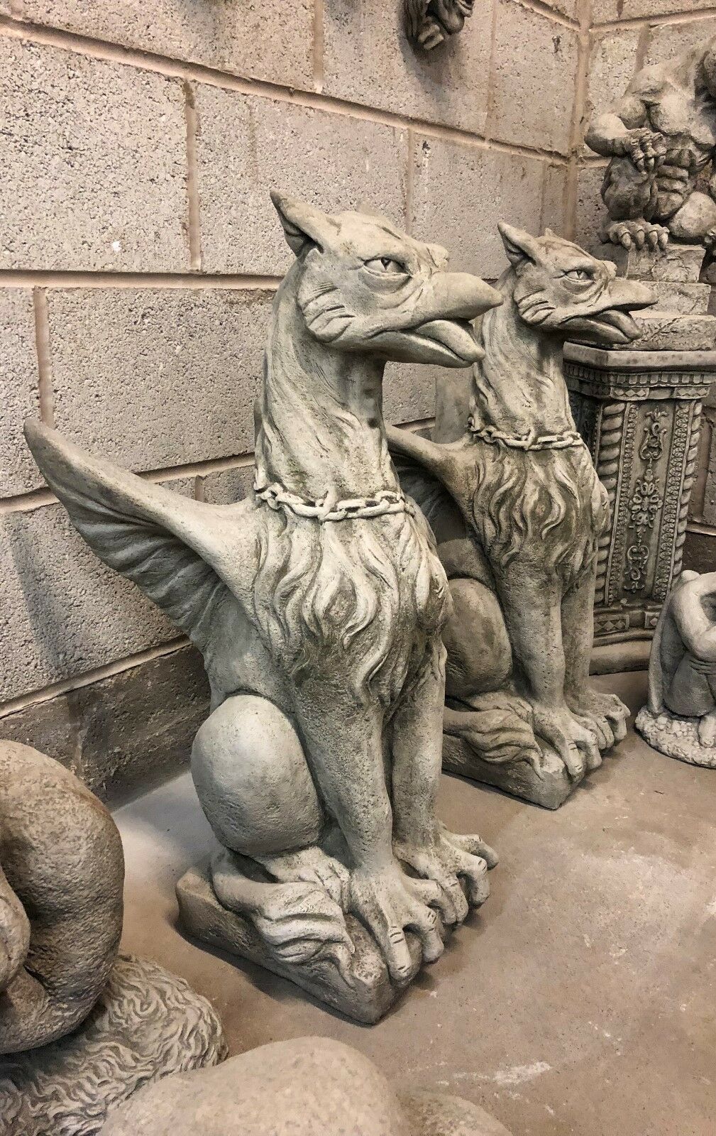 Side view of stone phoenix statues showing detailed wings and chained necks, perfect for outdoor garden decor or lawn ornamentation.