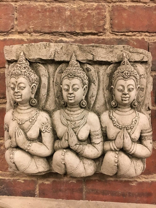 Stone Buddha wall plaque featuring three intricately carved figures in prayer pose. Ideal for garden decor, made from durable limestone.