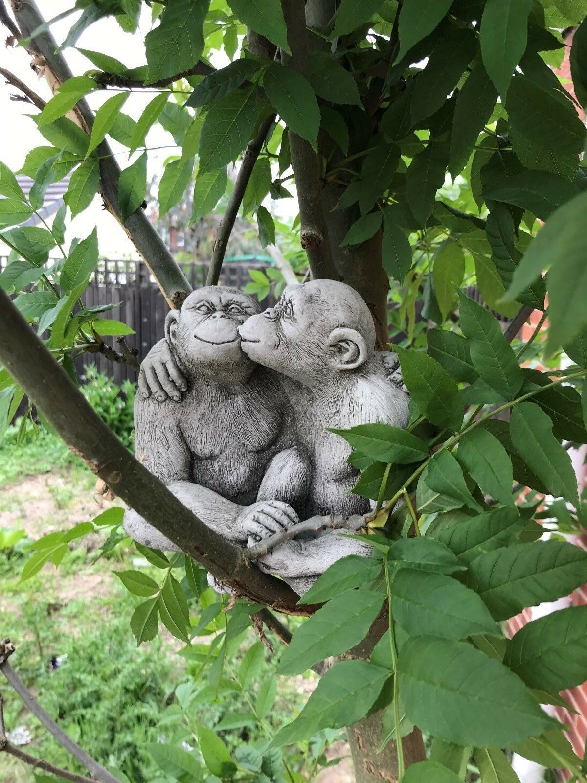 Garden Stone Monkey Ornament - Kissing Couple nestled in a tree, crafted from limestone for charming outdoor garden decor.