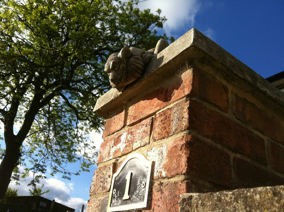 Gargoyle Garden Ornament with antique stone finish perched on a brick pillar, enhancing garden entrance decor with gothic charm and durability.