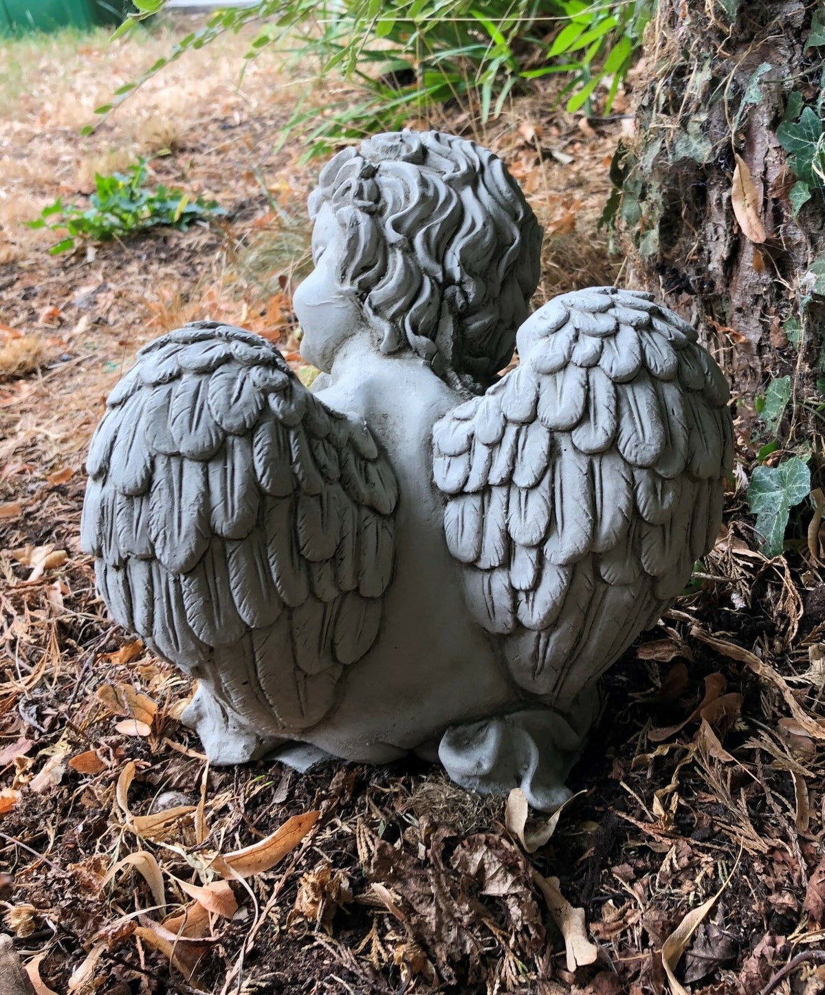 Back view of stone baby angel sculpture showing detailed feathered wings. Weather-resistant garden decor for year-round display.