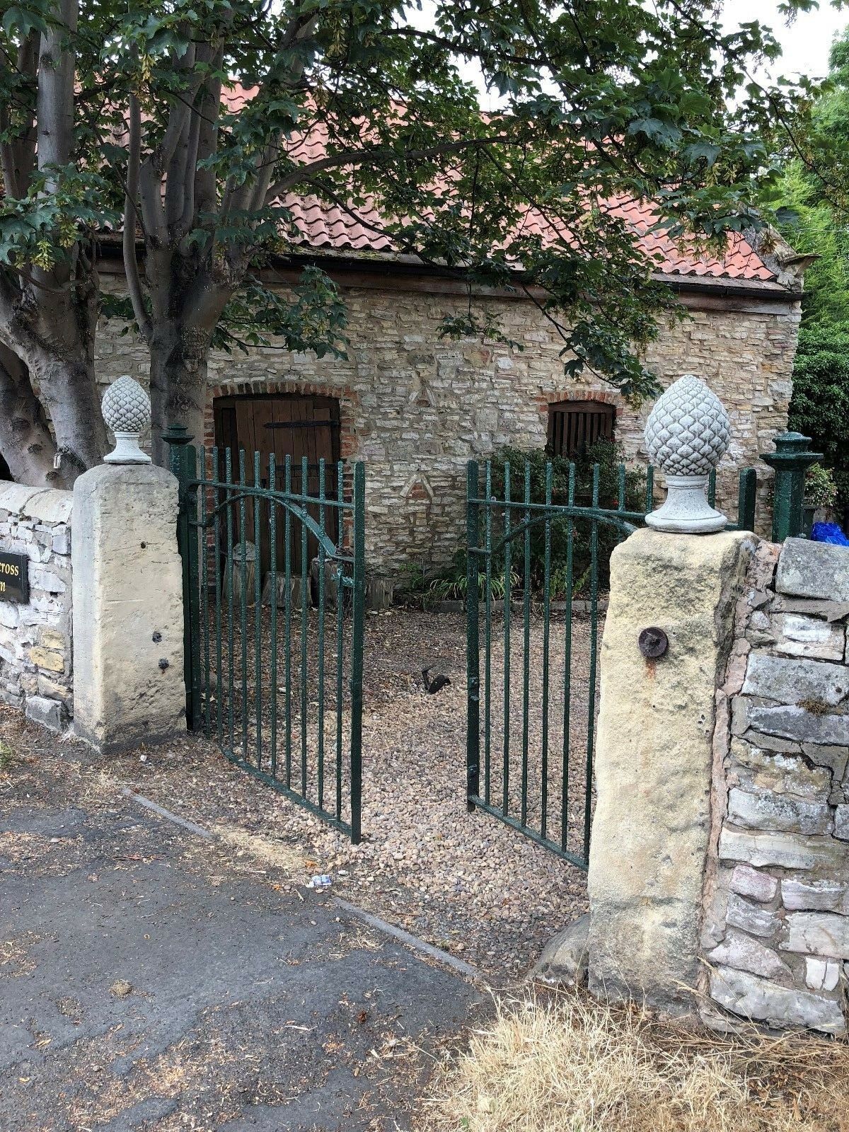 Pair of Stone Pineapple Finials mounted on gate pillars, enhancing entrance aesthetics with durable, decorative stone design.
