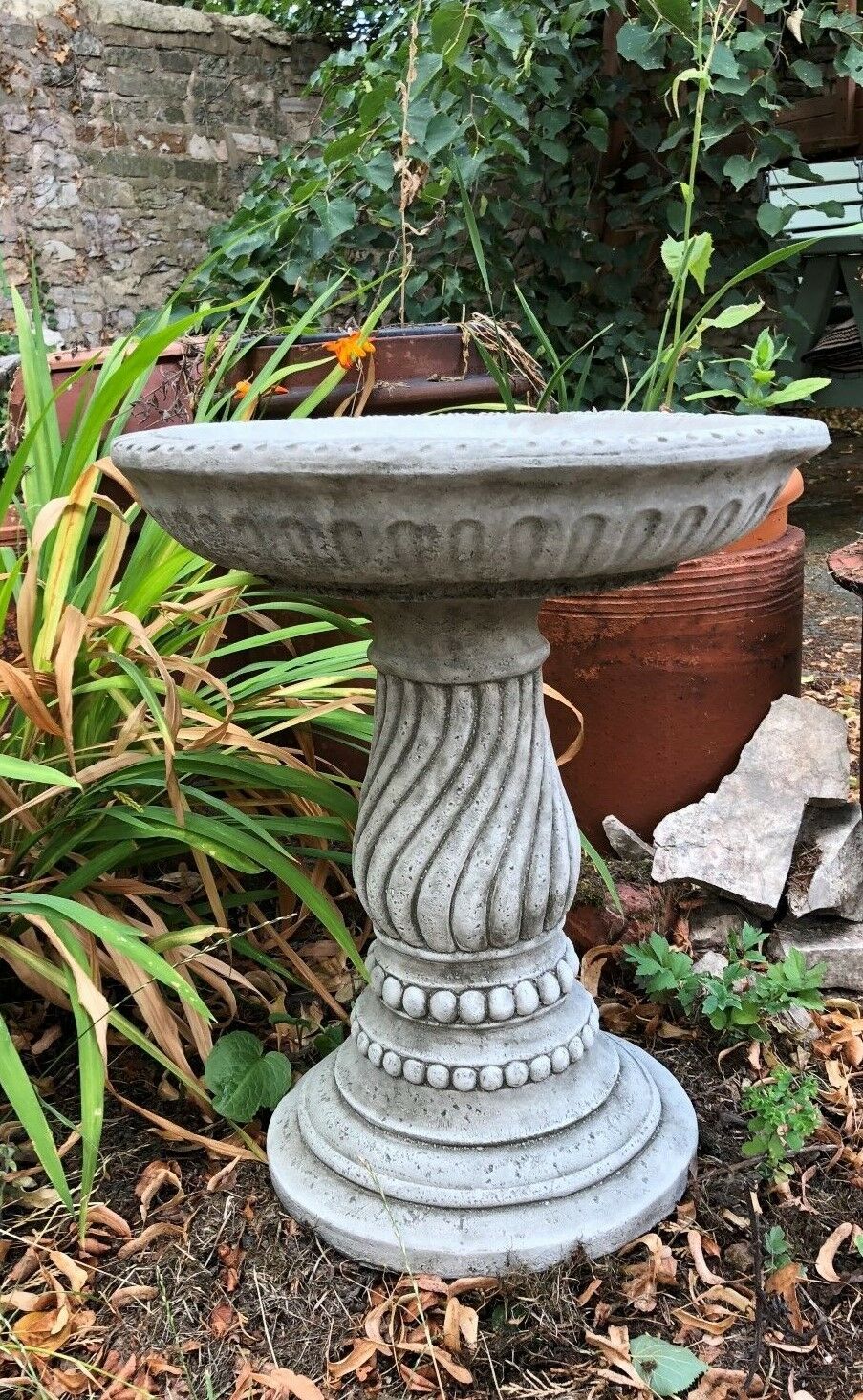 Decorative stone bird bath featuring a spiral twist base and detailed bowl rim, ideal for enhancing garden aesthetics and bird activity.