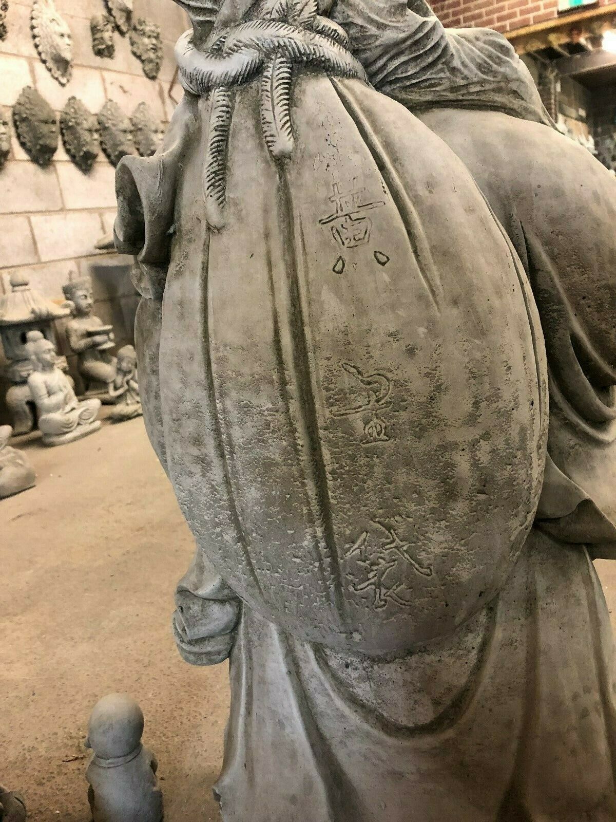 Close-up of Laughing Buddha Statue’s sack with engraved symbols, showcasing craftsmanship in this stone fortune decor piece.