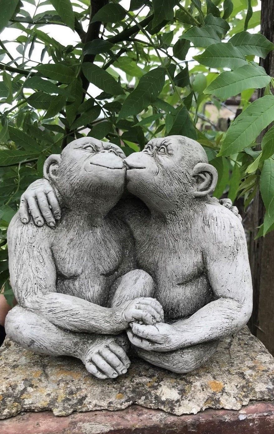 Limestone Kissing Monkey Couple Garden Ornament on stone base, ideal for enhancing patios or flowerbeds with romantic charm.