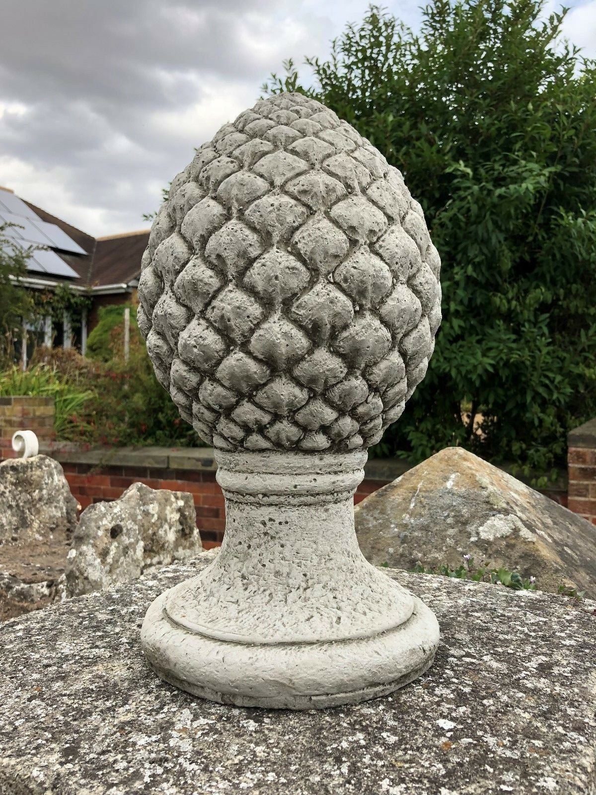 Close-up of a Stone Pineapple Finial on a stone wall, showcasing detailed texture and solid craftsmanship for garden decoration.
